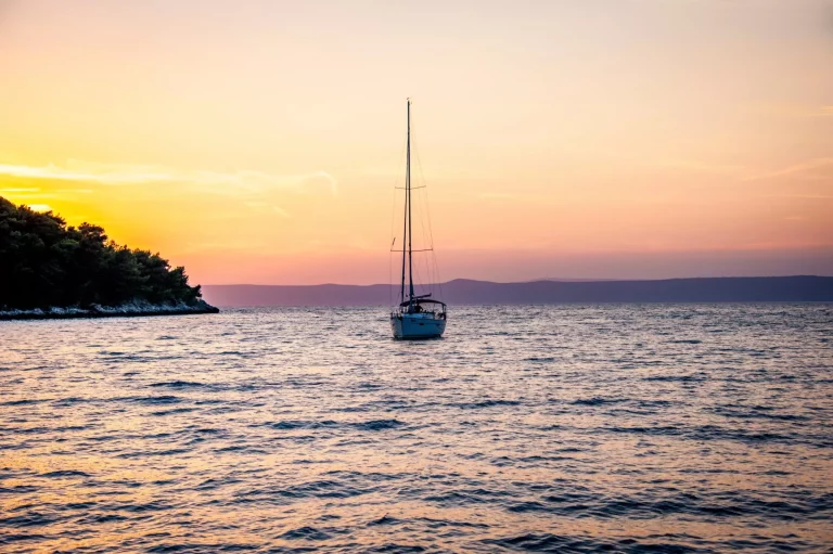 Zeilboot die de haven van Vela Luka binnenvaart tijdens de zonsondergang op het eiland Korčula in Kroatië.